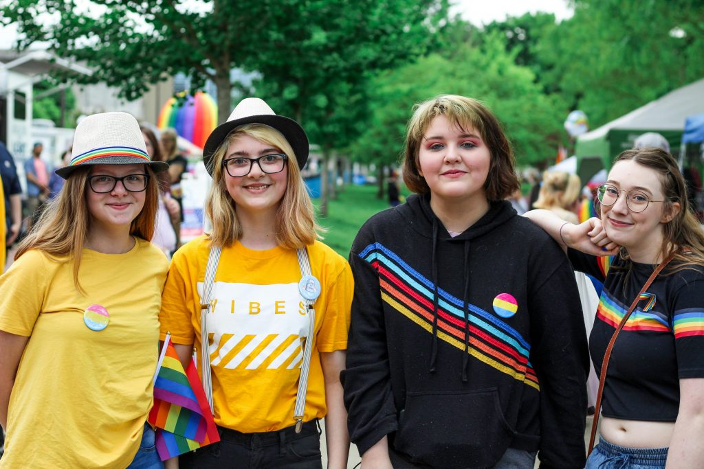 pexels-photo-2306841-2306841 Friends enjoying a vibrant pride parade with rainbow flags and colorful outfits outdoors.